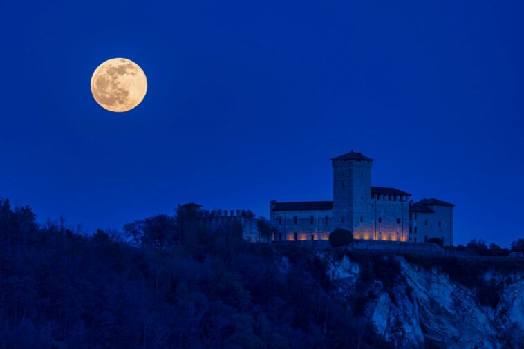 Majestic castle with a full moon at night, creating a dramatic and serene scene.