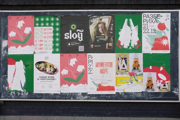 Colorful urban bulletin board with various artistic posters in multiple languages.