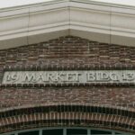 Architectural detail of a historic brick building facade with a market sign.