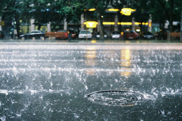 Vibrant rain scene on a Bucharest city street, showcasing splashing water and a lively urban atmosphere.