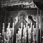 Black and white image of a religious altar with statues and candles in Carmona, Spain.
