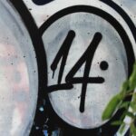 A detailed view of graffiti art featuring the number 14, with green leaves in the foreground.