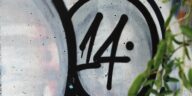 A detailed view of graffiti art featuring the number 14, with green leaves in the foreground.
