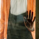 A spooky handprint left on a dusty glass door, conveying a sense of horror.