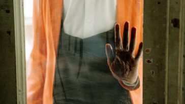 A spooky handprint left on a dusty glass door, conveying a sense of horror.