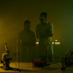 Researchers in a dimly lit lab conducting experiments with scientific equipment and test tubes.