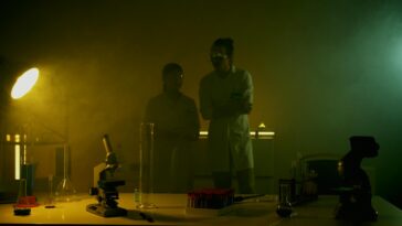 Researchers in a dimly lit lab conducting experiments with scientific equipment and test tubes.