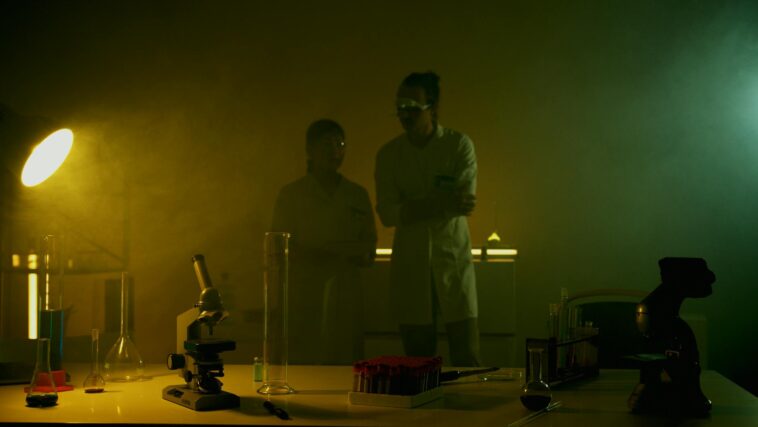 Researchers in a dimly lit lab conducting experiments with scientific equipment and test tubes.
