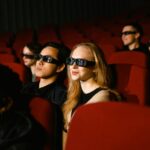 People in a cinema wearing 3D glasses, watching a film attentively.
