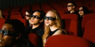 People in a cinema wearing 3D glasses, watching a film attentively.