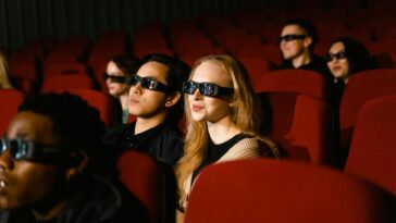 People in a cinema wearing 3D glasses, watching a film attentively.