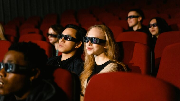 People in a cinema wearing 3D glasses, watching a film attentively.