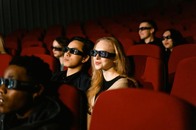 People in a cinema wearing 3D glasses, watching a film attentively.