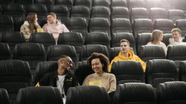 Young adults having fun in an empty movie theater with popcorn.