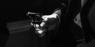 Black and white image capturing a suspenseful noir scene with a handgun.