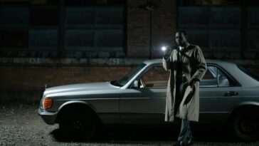 Detective conducting a night investigation by a car with a flashlight.