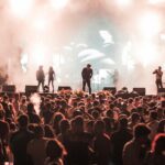 Lively crowd enjoying a nighttime concert with dynamic lighting and energetic performers on stage.