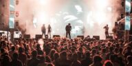 Lively crowd enjoying a nighttime concert with dynamic lighting and energetic performers on stage.