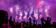 Vibrant EDM concert scene with fireworks, smoke, and enthusiastic crowd enjoying the music.