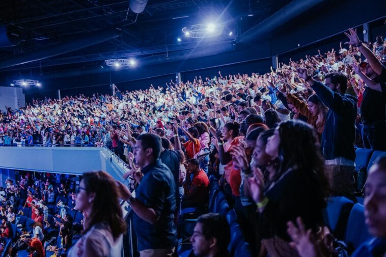 Energetic crowd at a music concert inside a large arena. Perfect capture of audience excitement.