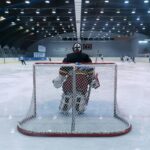 Dynamic scene of a thrilling ice hockey match with goalie ready in front of the goal.