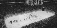 Black and white overhead shot of a thrilling ice hockey game with a full audience in an indoor arena.