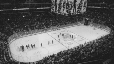 Black and white overhead shot of a thrilling ice hockey game with a full audience in an indoor arena.