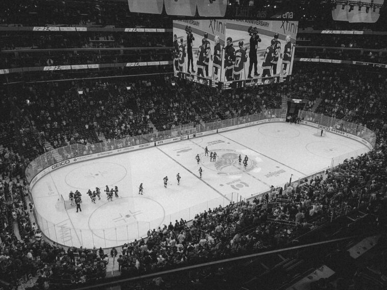 Black and white overhead shot of a thrilling ice hockey game with a full audience in an indoor arena.