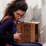 Woman playing accordion on a stone street in Porto, Portugal. Captivating street performance.