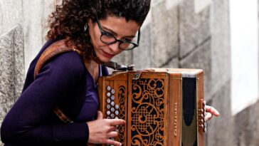 Woman playing accordion on a stone street in Porto, Portugal. Captivating street performance.
