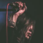 Energetic close-up of a musician gripping a microphone during a live performance.