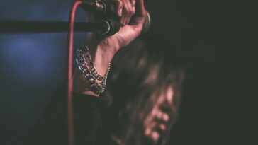 Energetic close-up of a musician gripping a microphone during a live performance.