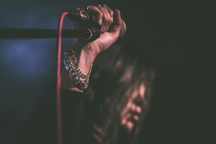 Energetic close-up of a musician gripping a microphone during a live performance.