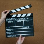 Close-up of hands holding a Universal Studios clapboard on a cork backdrop, ready for filming.