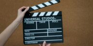 Close-up of hands holding a Universal Studios clapboard on a cork backdrop, ready for filming.