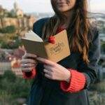 Young woman with a journal enjoys a scenic view from a hilltop.