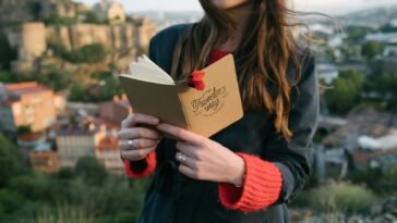 Young woman with a journal enjoys a scenic view from a hilltop.