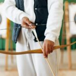 A person prepares to shoot an arrow in an indoor archery range, focusing on technique and precision.