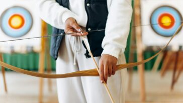 A person prepares to shoot an arrow in an indoor archery range, focusing on technique and precision.