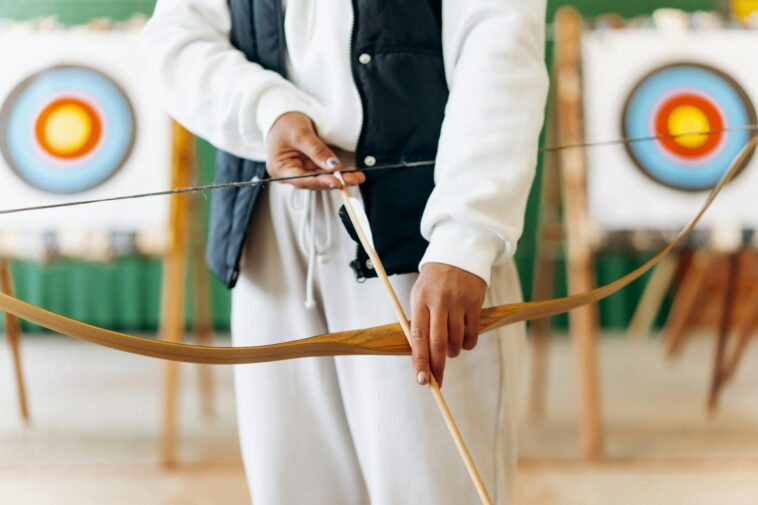 A person prepares to shoot an arrow in an indoor archery range, focusing on technique and precision.