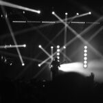 Captivating black and white image of a guitarist performing with dramatic lighting effects on stage.