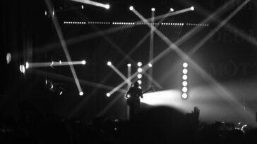 Captivating black and white image of a guitarist performing with dramatic lighting effects on stage.