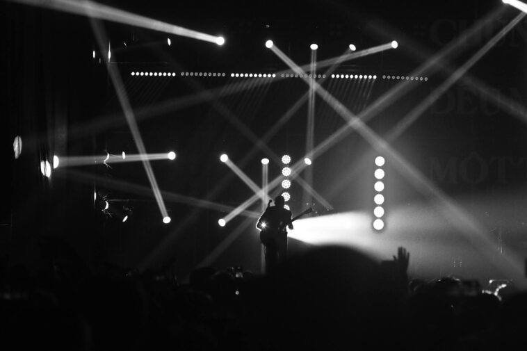 Captivating black and white image of a guitarist performing with dramatic lighting effects on stage.