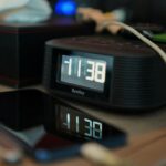 A digital clock reading 11:38 with reflections on a smartphone screen.