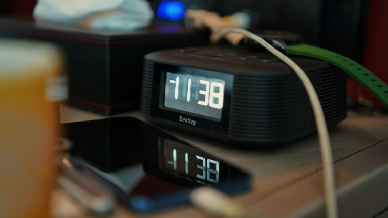 A digital clock reading 11:38 with reflections on a smartphone screen.