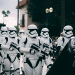 Group of stormtroopers marching outdoors during a cosplay event at a theme park.