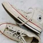 A pair of vintage Converse sneakers on a marble surface, showcasing classic style.