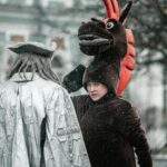 Two people in costume converse during snowfall, adding a whimsical touch to a winter's day.
