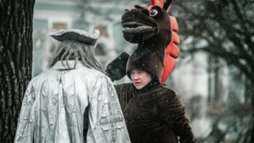 Two people in costume converse during snowfall, adding a whimsical touch to a winter's day.