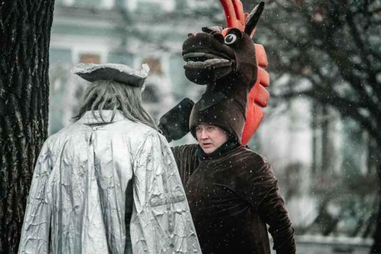Two people in costume converse during snowfall, adding a whimsical touch to a winter's day.